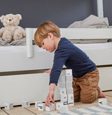 Barn leger med bogstavklodser ved Manis-h køjeseng med hvid sengehest.