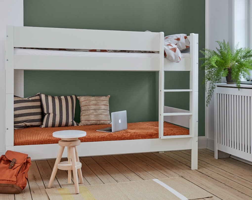 Huxie hvid Arkas køjeseng med laptop, pude og skammel i rum med grøn væg